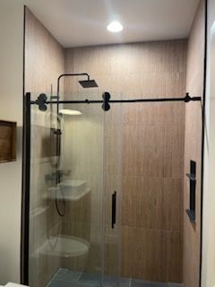 A bathroom with a sliding glass shower door , toilet , sink and shower head.
