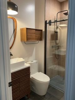 A bathroom with a toilet , sink and shower.