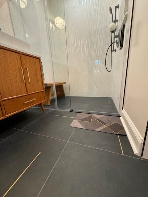 A bathroom with a walk in shower and a wooden vanity.