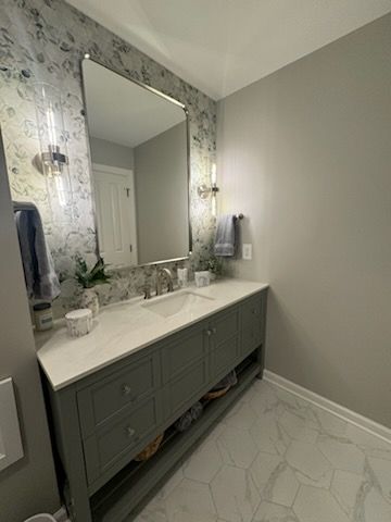 A bathroom with a sink , mirror and towel rack.