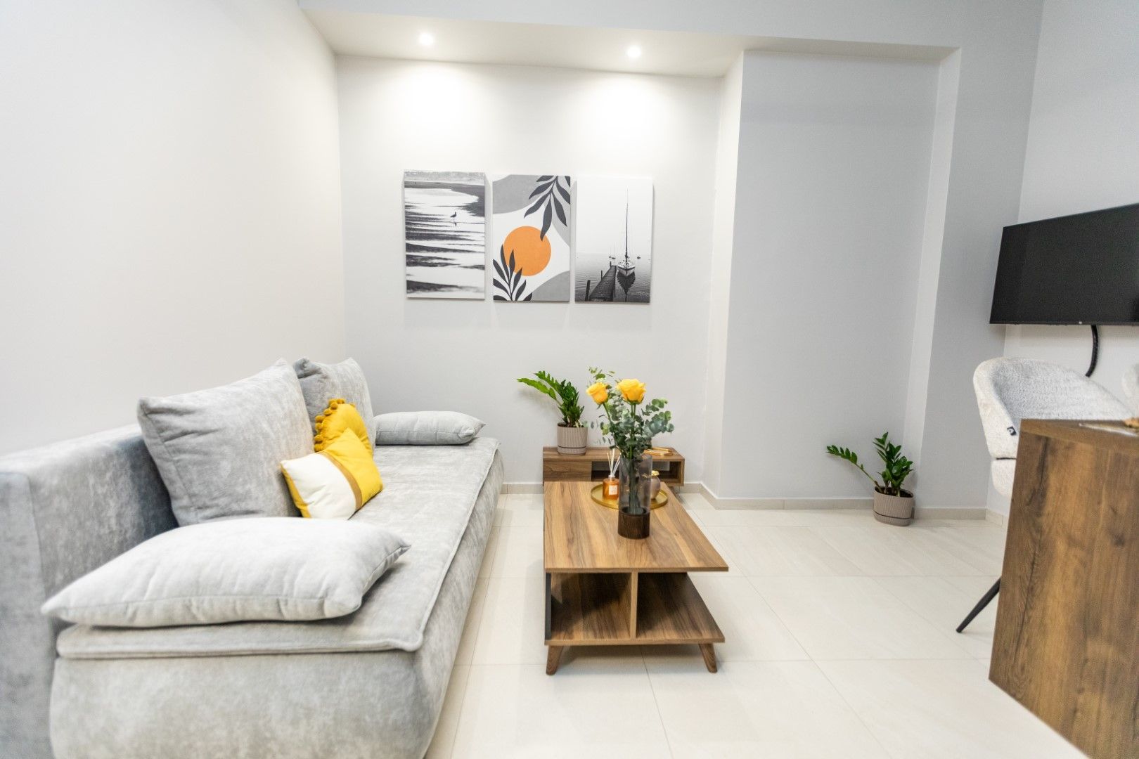 Cozy living room with gray couch, wooden coffee table, art, and a mounted TV.