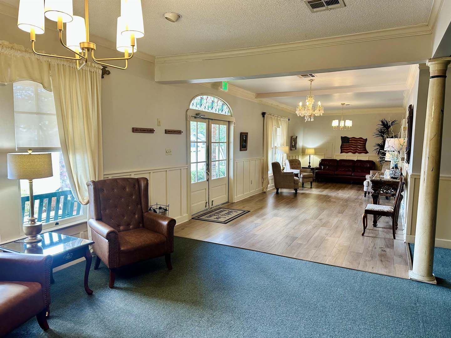 An interior shot of a well-lit reception area with seating, wooden floors, and chandeliers.