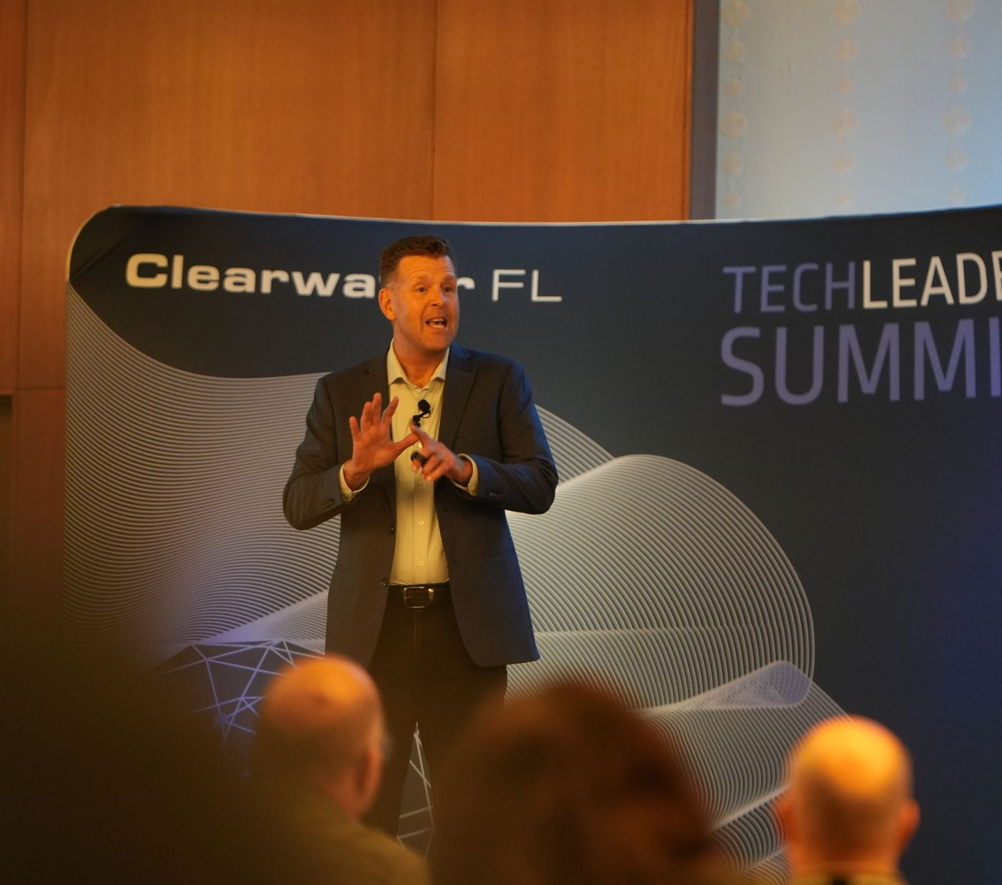Pete Behrens in suit on stage delivering a keynote at the Tech Leader Summit in Clearwater Florida.