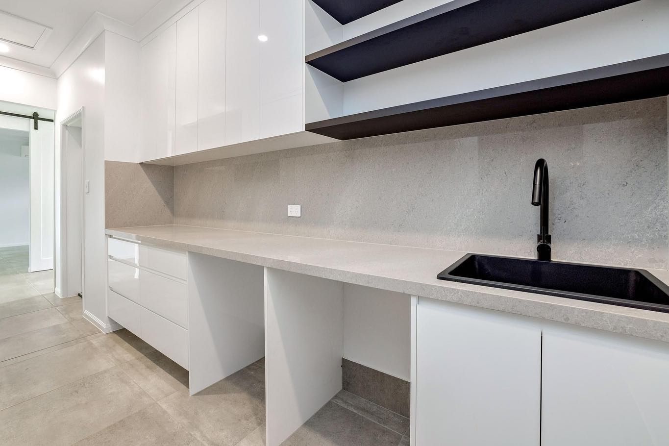 Modern White Roon With Long Countertop, Black Sink And Faucet, And Open Shelving — Kitchens by CCJS in Bungalow, QLD