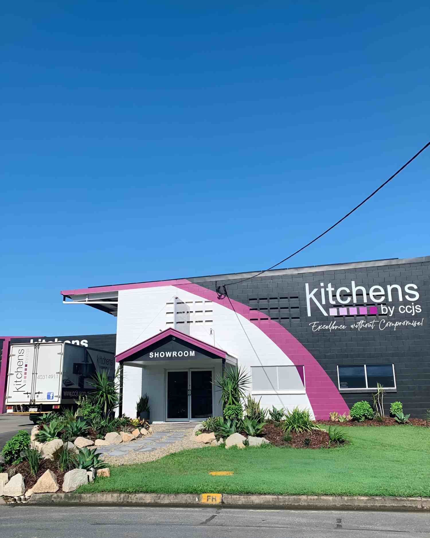 A Pink and White Building With a Sign That Says Kitchens on It — Kitchens by CCJS in Bungalow, QLD