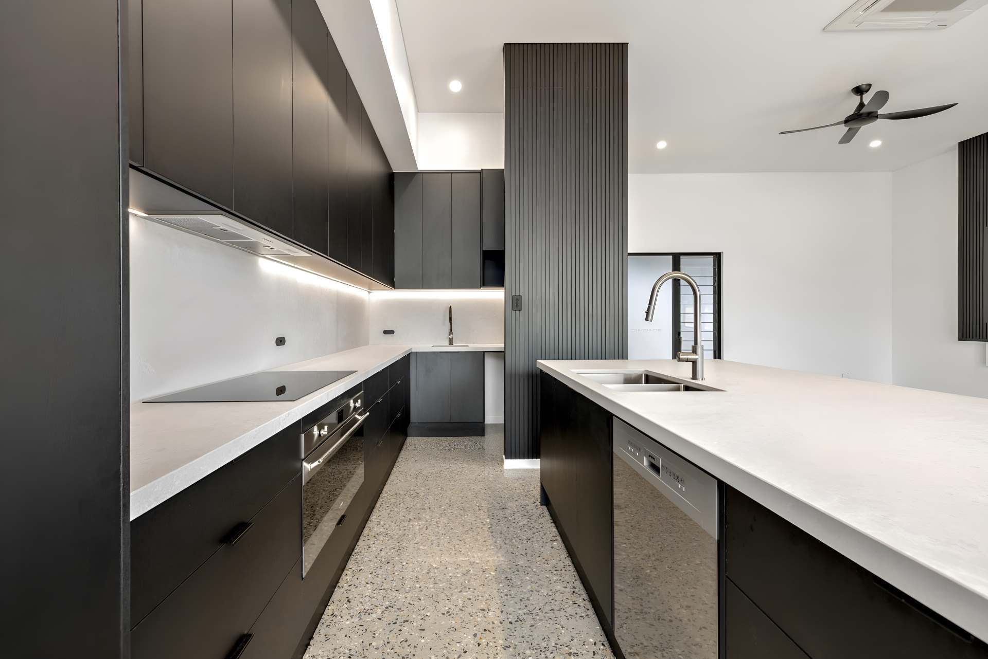 A Kitchen With Black Cabinets and White Counter Tops and a Ceiling Fan — Kitchens by CCJS in Bungalow, QLD