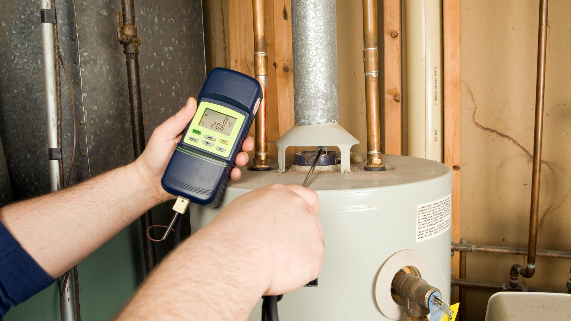 a person is holding a thermometer in front of a water heater .