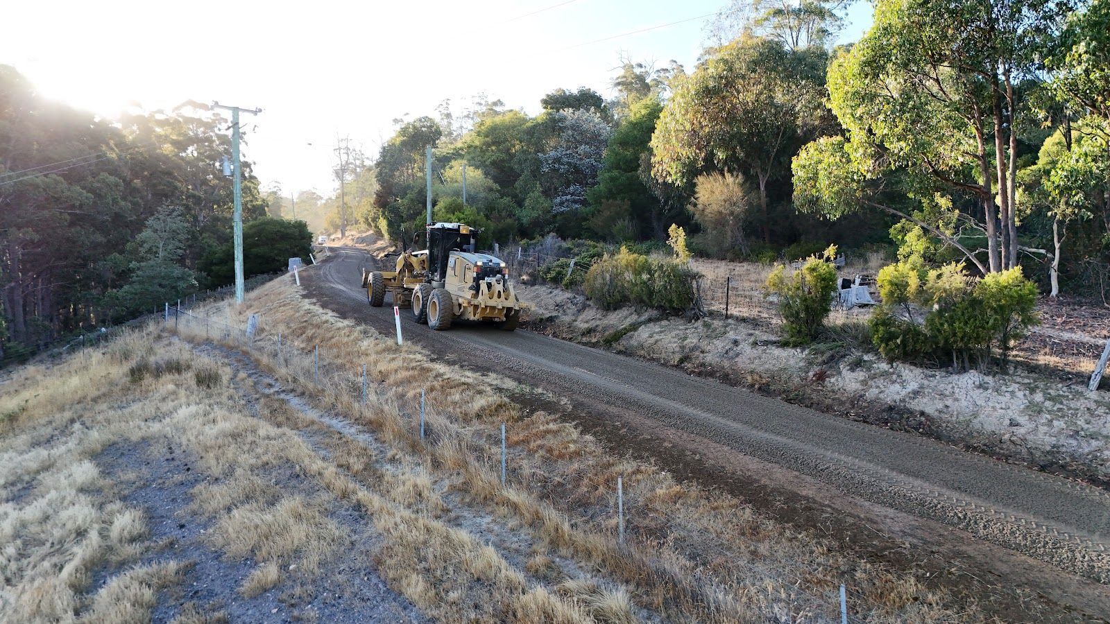 Yellow construction loader viewed from the front with a cab labeled “PUGGANS” and raised arms.