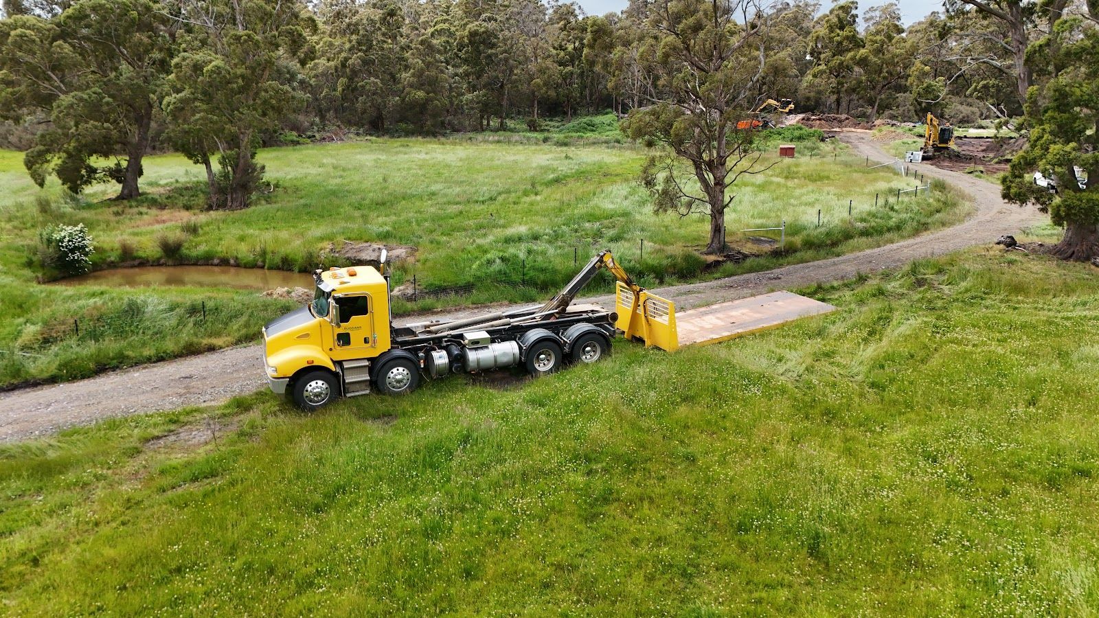 Yellow construction loader beside stacked large concrete pipes on a worksite under a cloudy sky