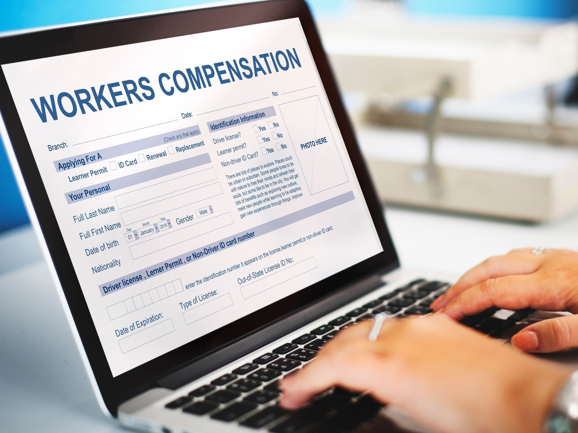 Person typing on a laptop with a workers' compensation form displayed on the screen.