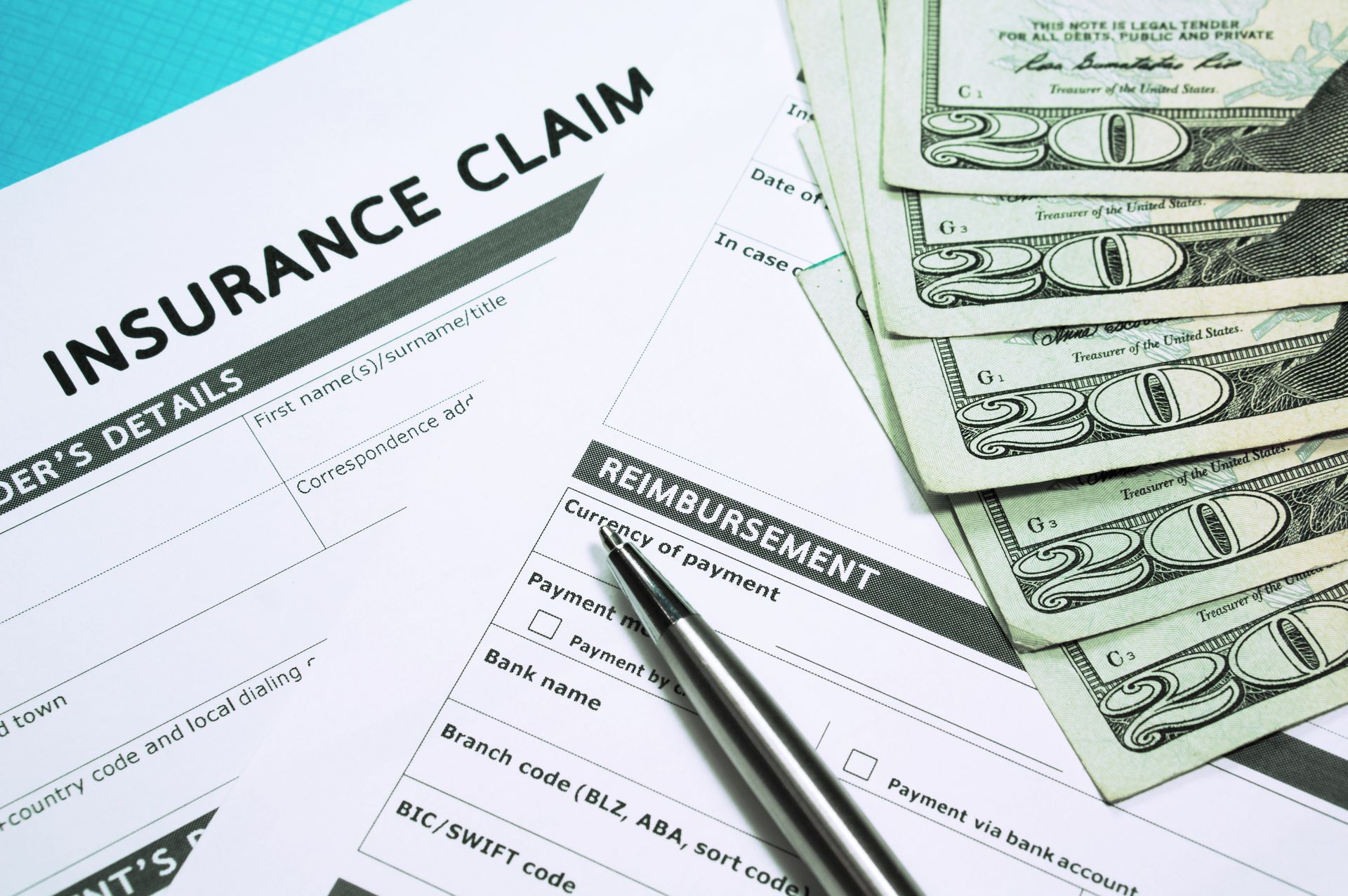 Insurance claim form with pen and stack of cash, likely for reimbursement.