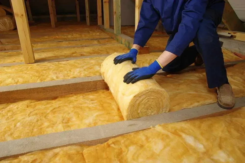 Person Installing Yellow Insulation in an Attic — Kev's Group QLD in Kawana, QLD Person Installing Yellow Insulation in an Attic — Kev's Group QLD in Kawana, QLD