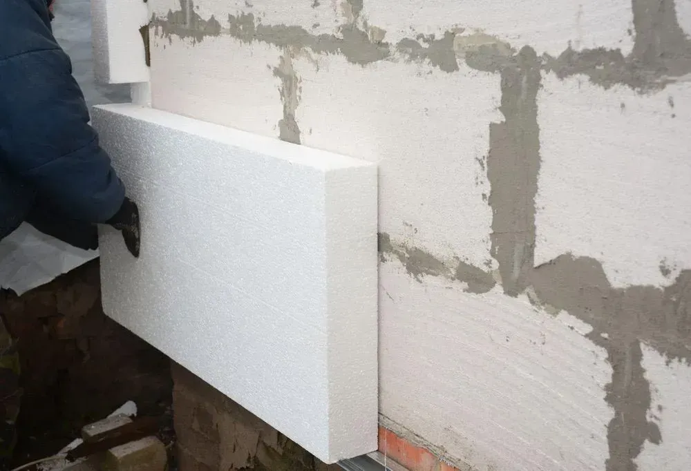 Person Installing White Foam Insulation on a Brick Wall — Kev's Group QLD in Kawana, QLD Person Installing White Foam Insulation on a Brick Wall — Kev's Group QLD in Kawana, QLD