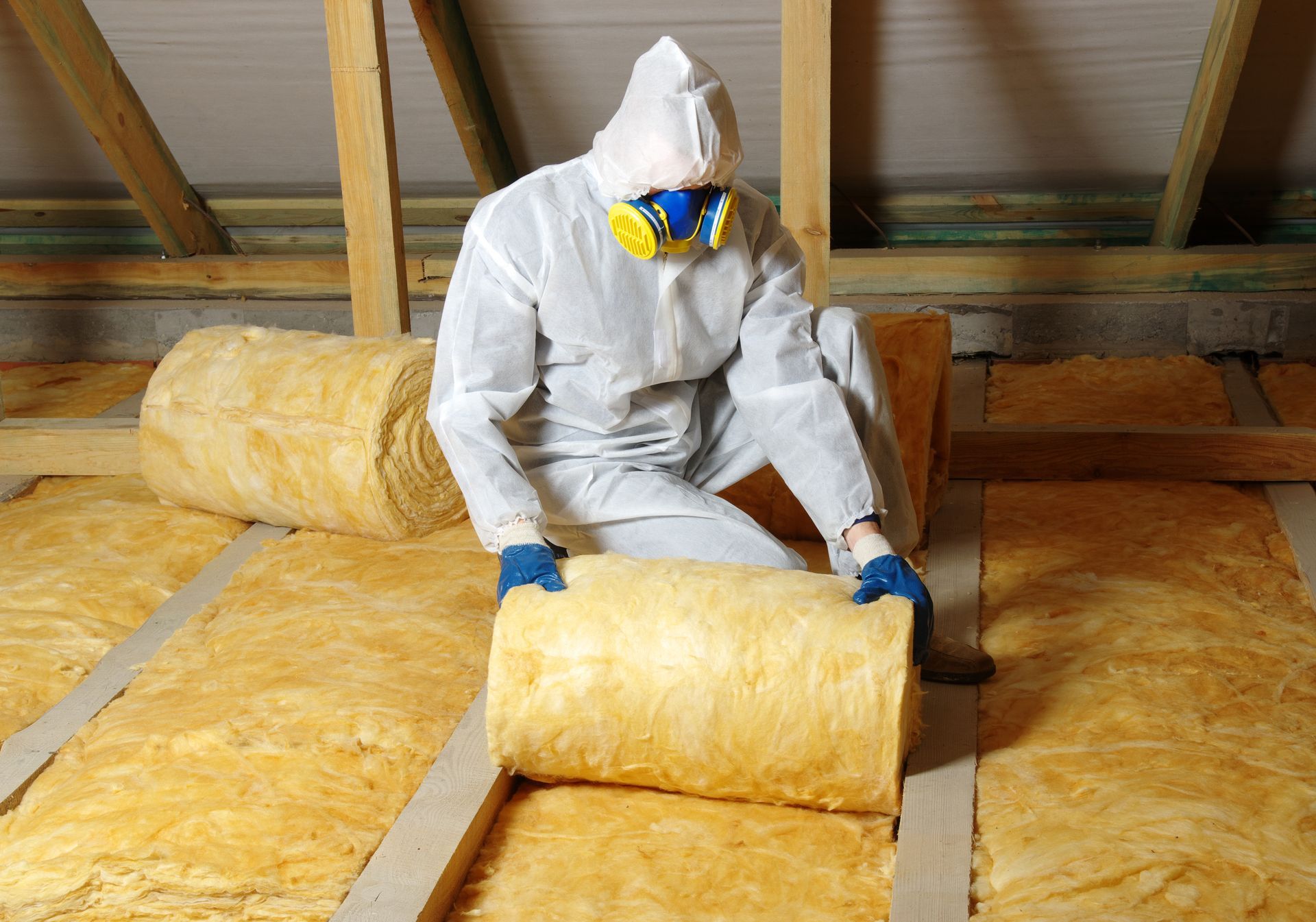 Person in Protective Suit Installing Insulation in an Attic — Kev's Group QLD in Kawana, QLD