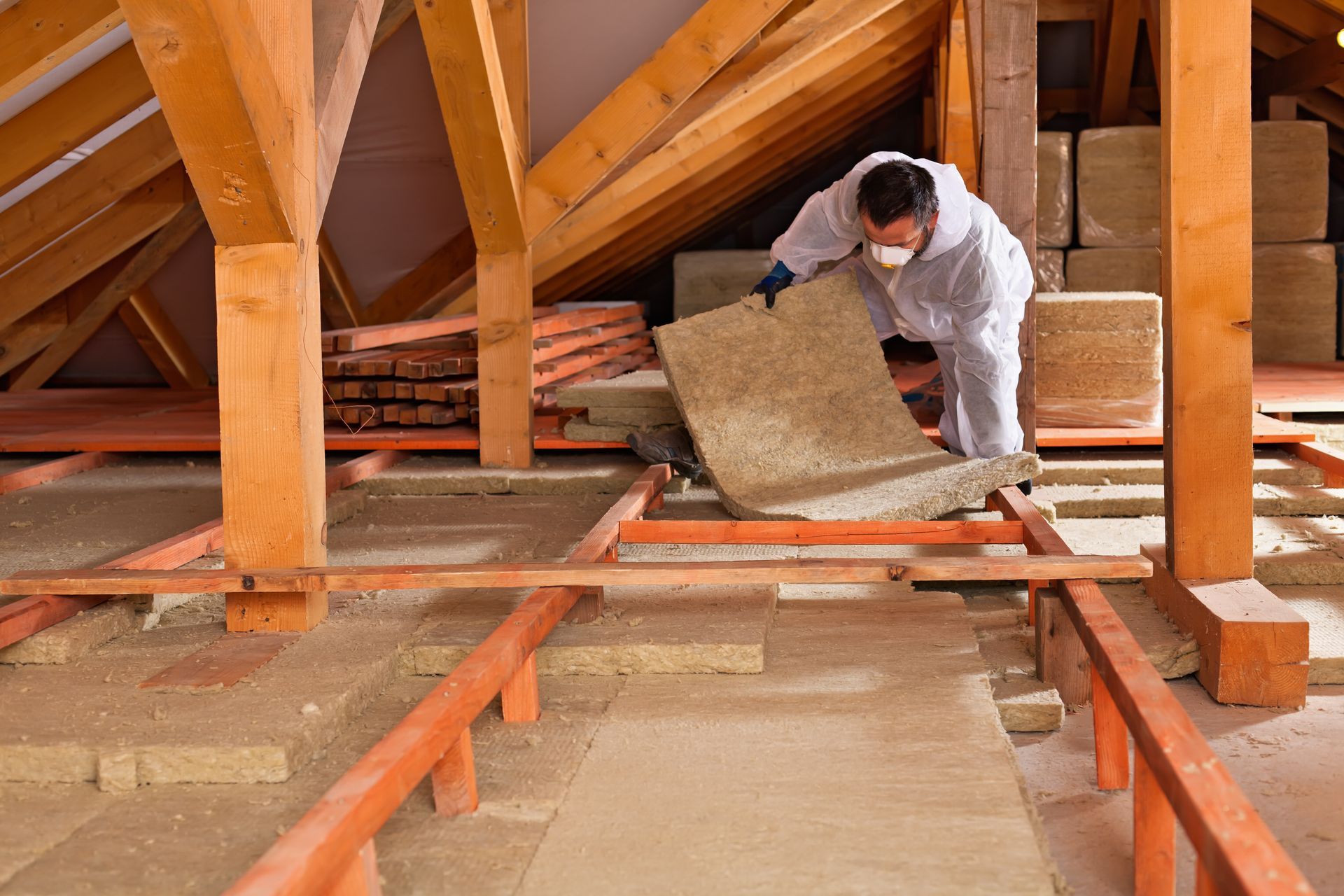 Man in Protective Suit Installing Insulation in an Attic — Kev's Group QLD in Kawana, QLD
