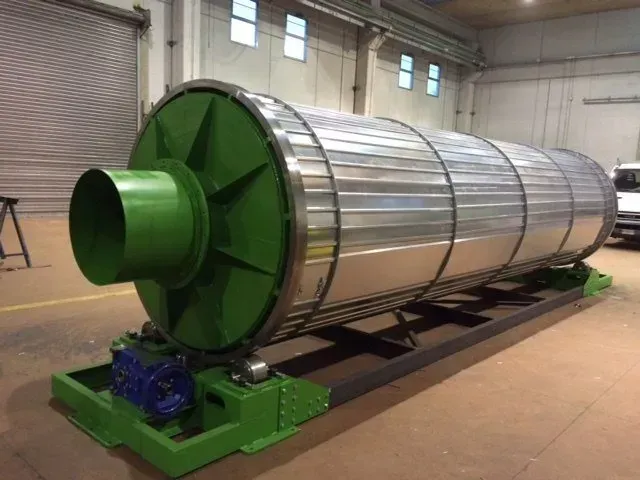 Grande tamburo rotante industriale, in metallo argentato con base e terminali verdi.