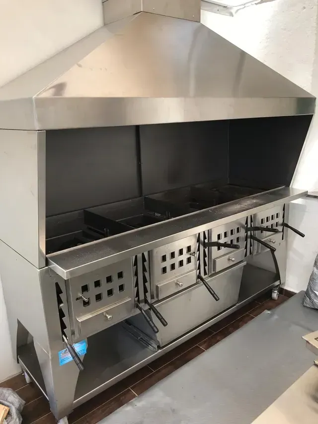 Forno da cucina commerciale in acciaio inox con cappa aspirante; più scomparti e cassetti.