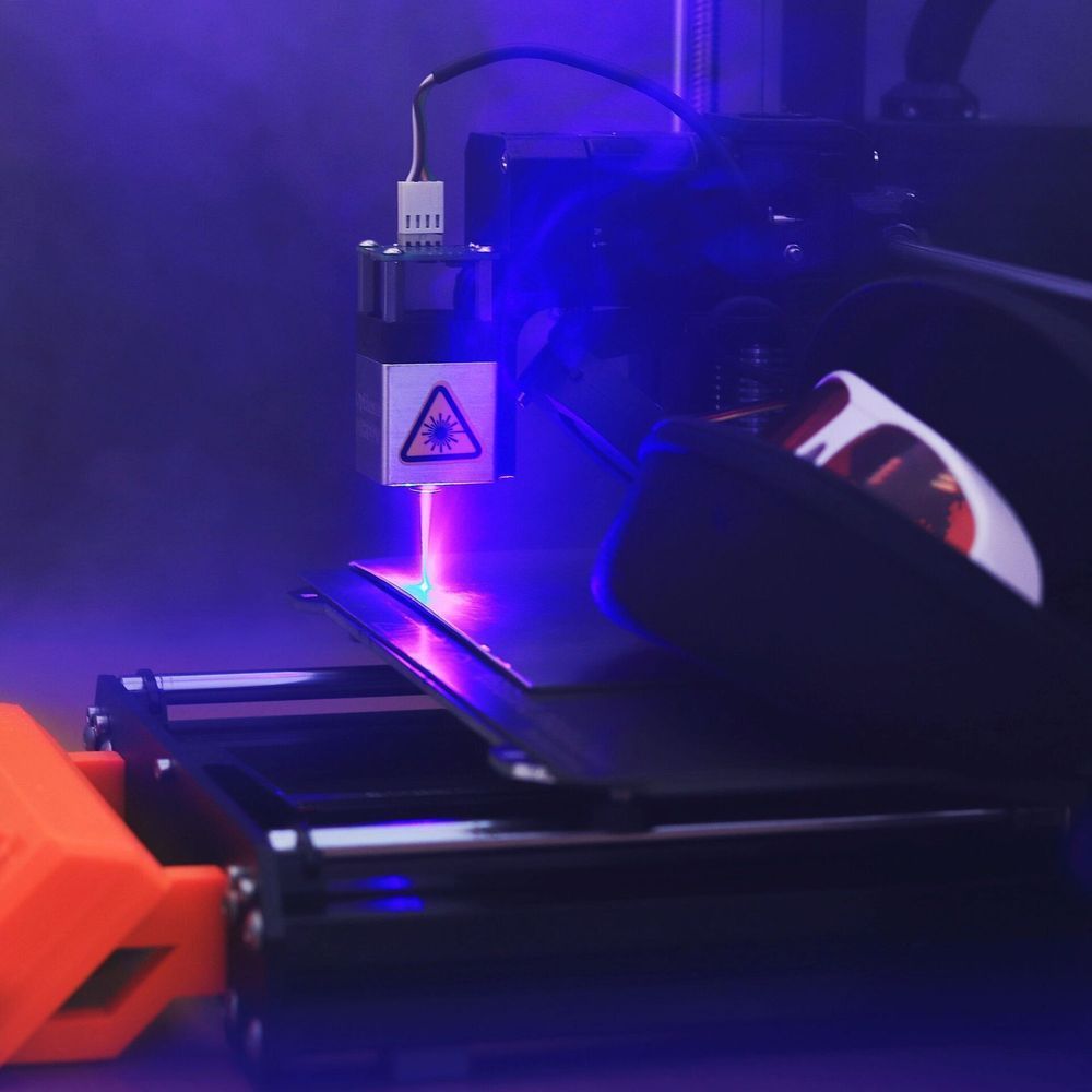 Incisore laser in azione, che emette un raggio blu brillante su una superficie scura.