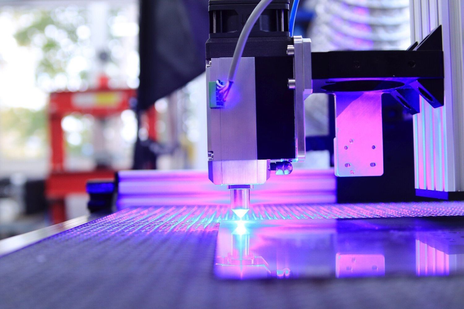 Taglierina laser in funzione, emette luce blu e taglia una superficie riflettente.