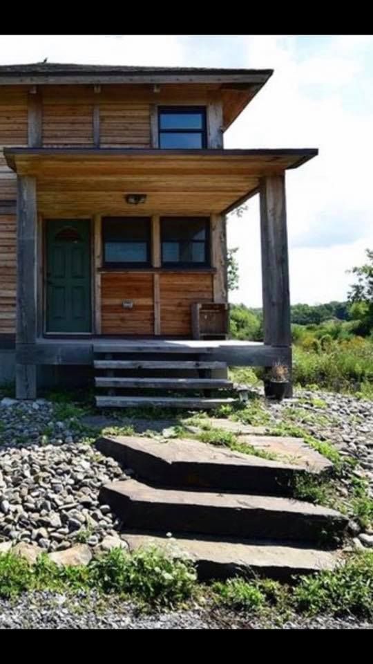 A wooden house with stairs leading up to the front door .