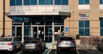Storefront entrance with parked cars in front and a sign above the door