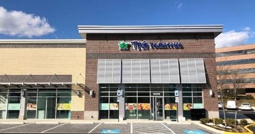 Storefront of a FedEx location with glass entrance and parking spaces in front