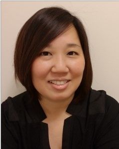Smiling person with short dark hair in a black top against a beige background