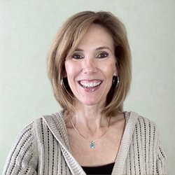 Smiling woman in a beige sweater against a plain light background