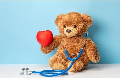 Teddy bear with a stethoscope holding a red heart on a blue background