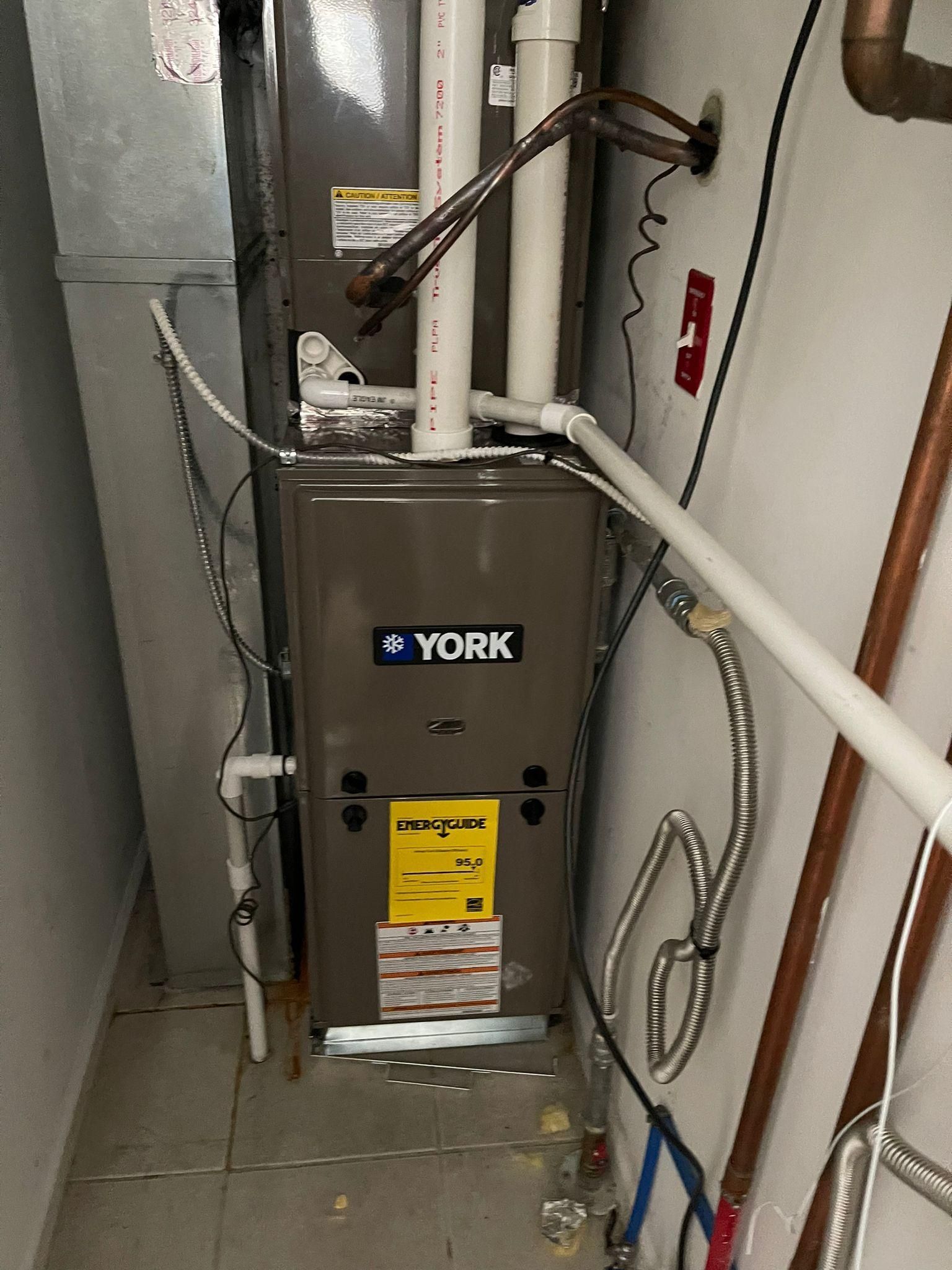 Technician repairing a white water heater with a wrench indoors