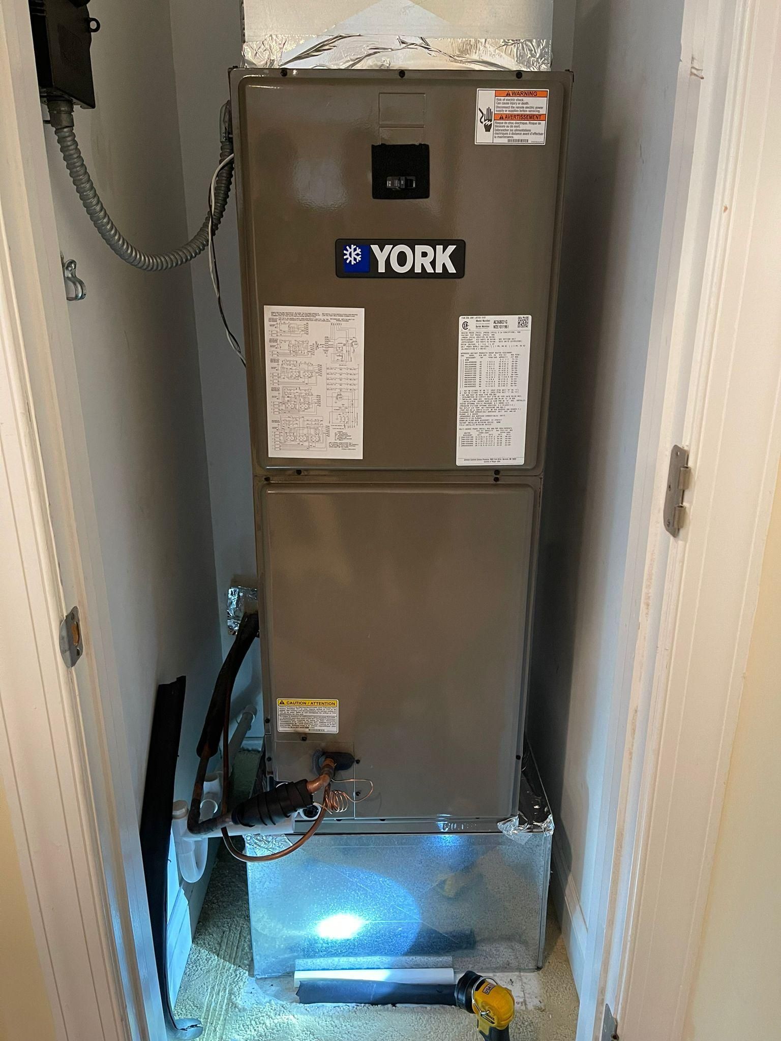 York furnace in a narrow utility closet, with a flashlight illuminating the floor.