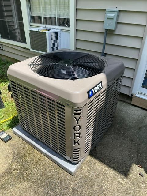 Outdoor York air conditioner unit beside a house wall with a window and electrical meter.