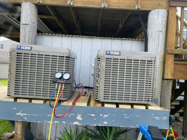 Two York outdoor AC units on a raised wooden platform with connected gauges and hoses