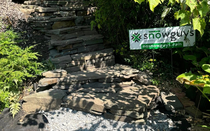 Stone steps beside dense greenery, with a small white sign reading “Snowy’s.”