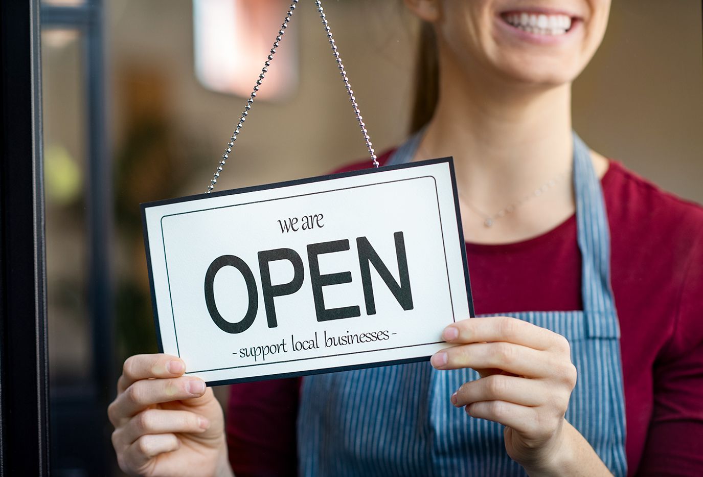Local business owner smiling and flipping store sign to open