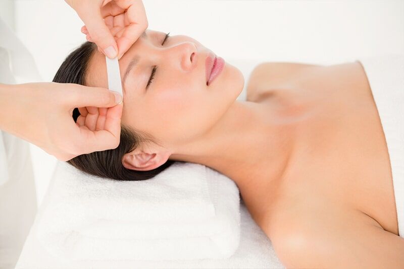 A woman is getting her eyebrows waxed at a beauty salon.