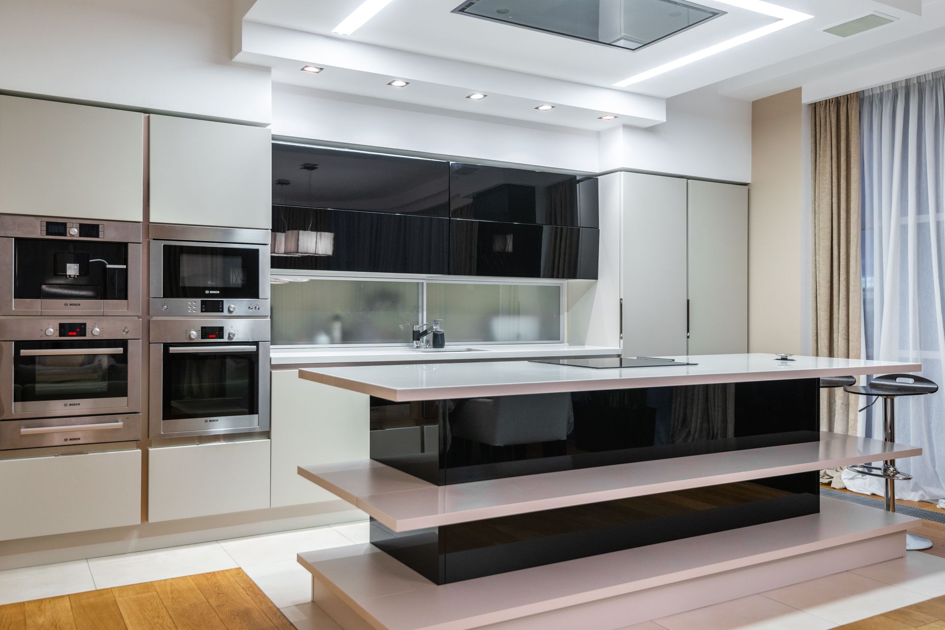 Modern kitchen with glossy cabinets, built-in ovens, and a large island under bright ceiling lights