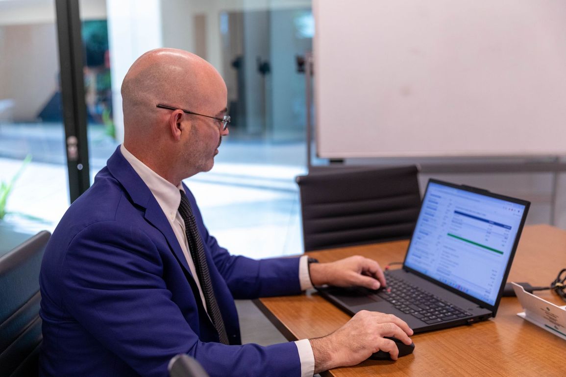 Man in blue blazer using a laptop at a conference table in an office