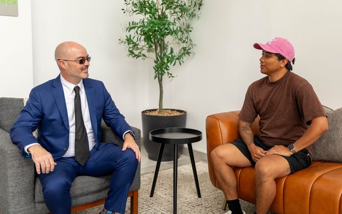 Two people seated in a bright office lounge, facing each other in conversation.