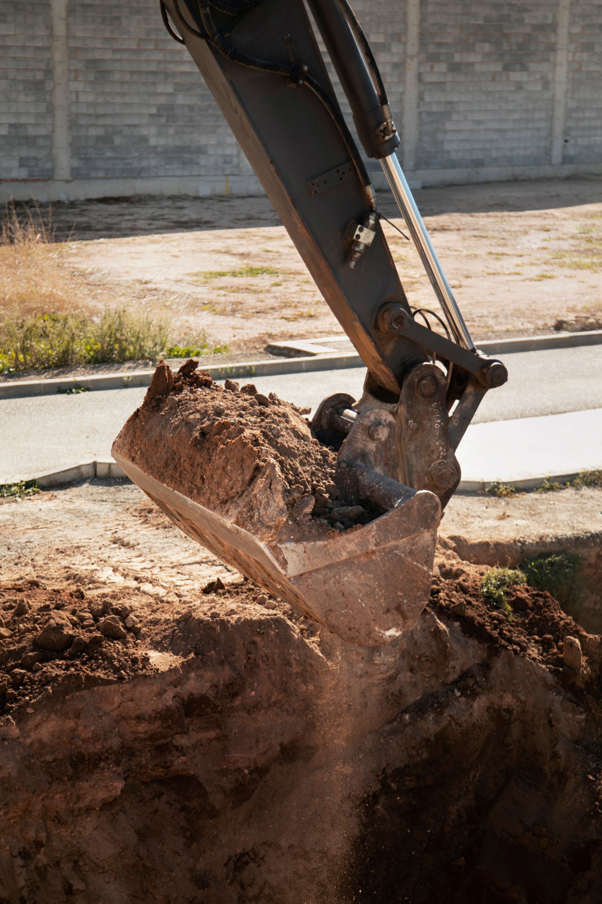 Excavator digging a hole, scooping and dumping dirt. Outdoor setting, daytime.