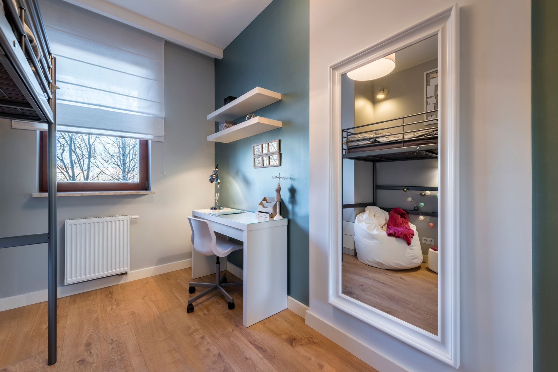 A bedroom with a desk , bunk bed and a large mirror.