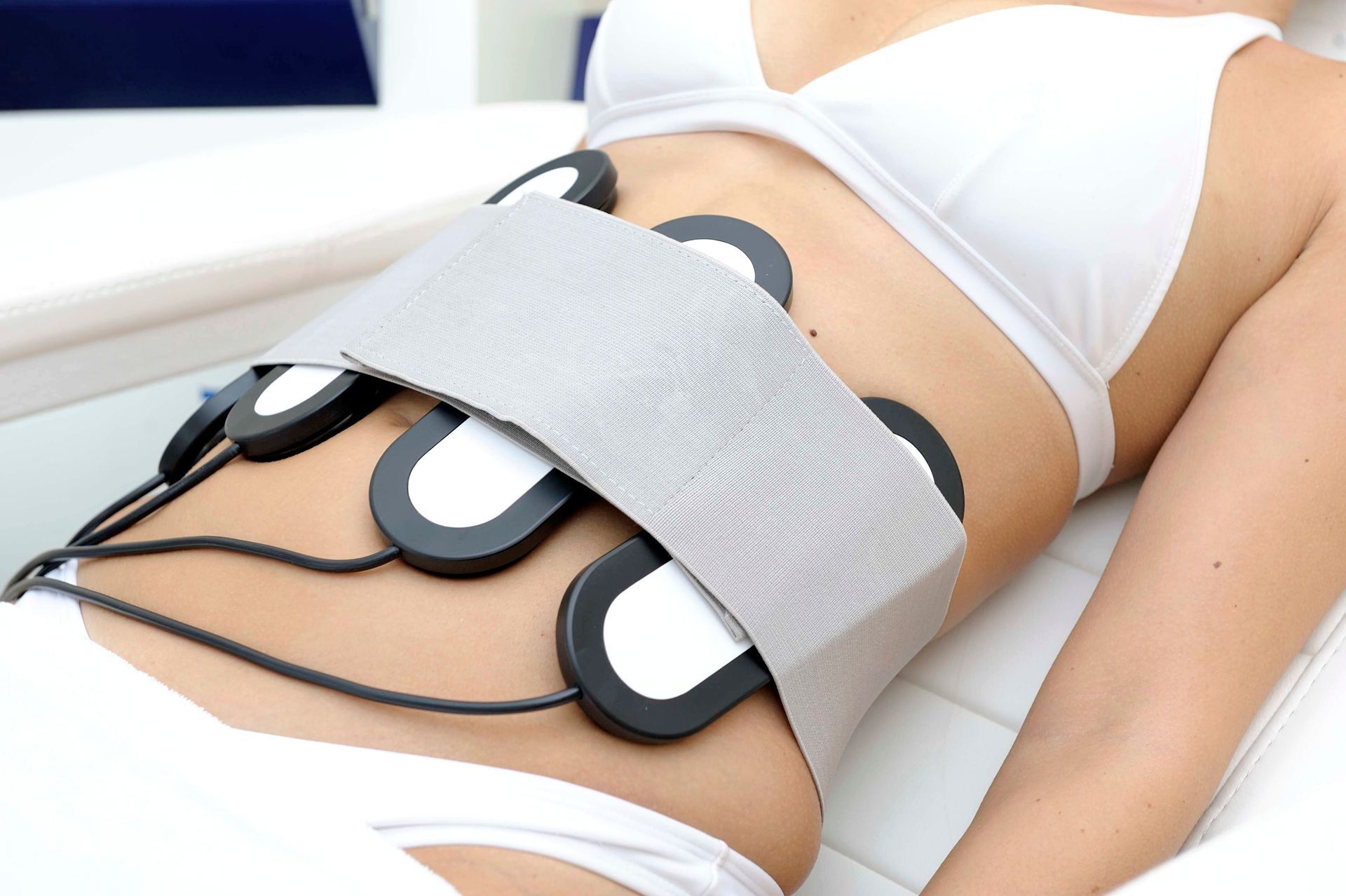 A woman is laying on a bed with a device on her stomach