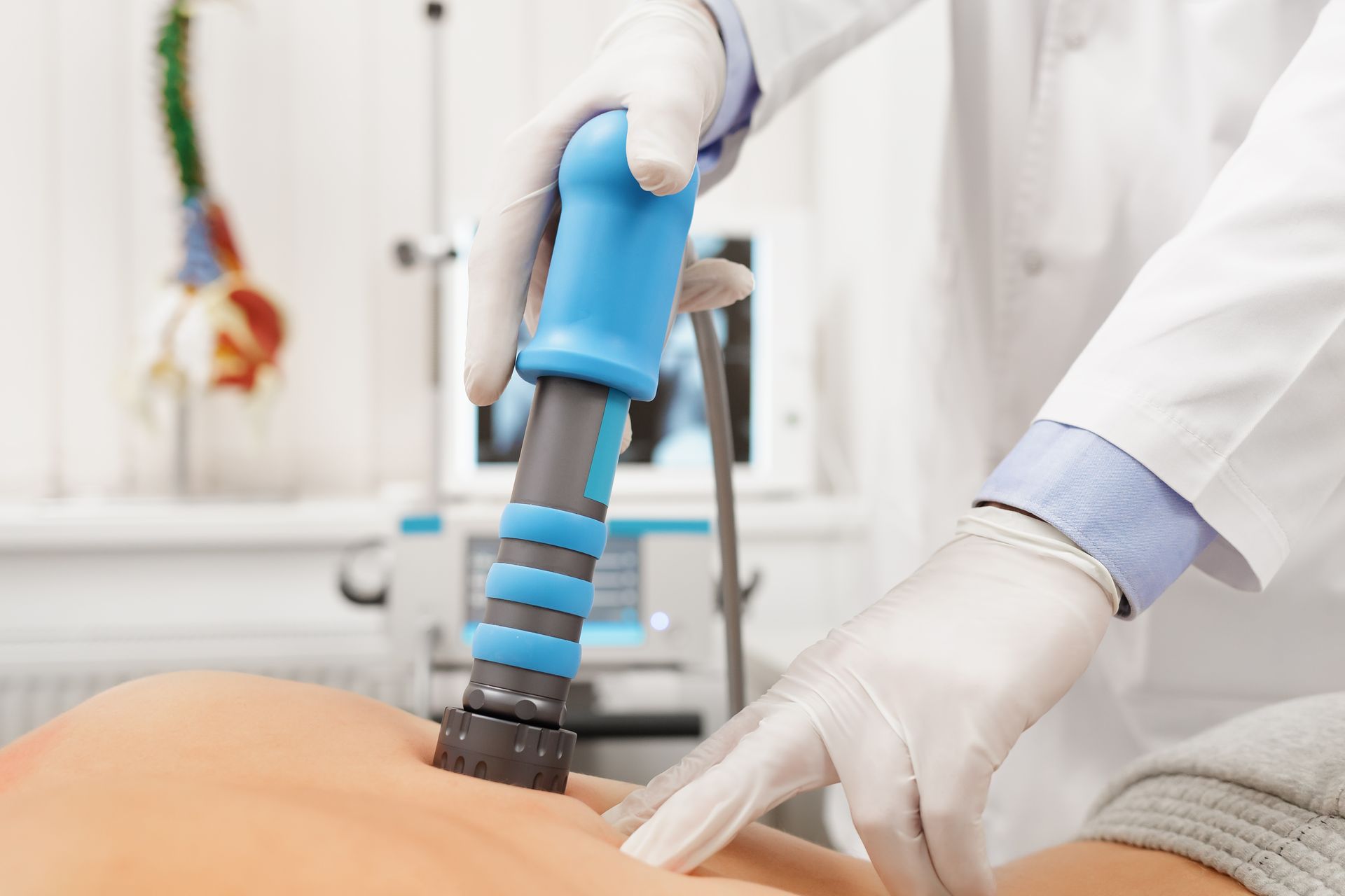 A doctor is using a machine on a patient 's back.