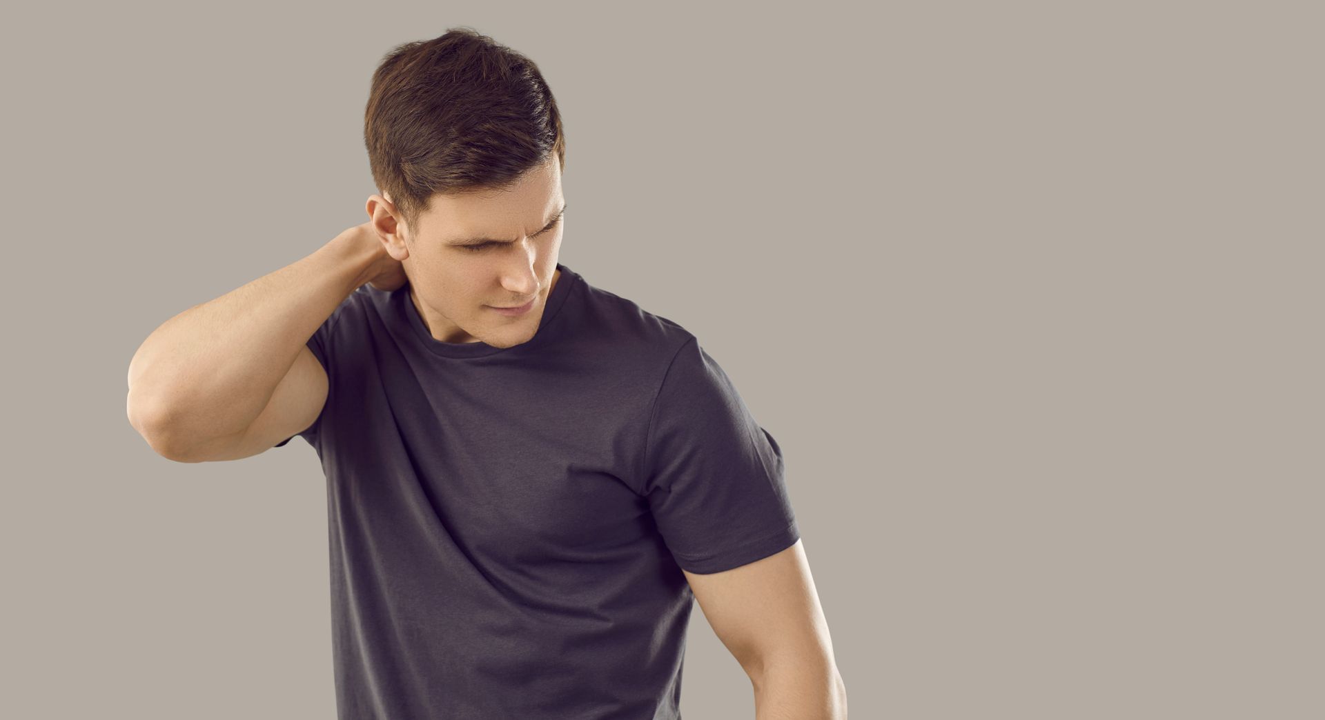 A man in a black t-shirt is holding his neck.
