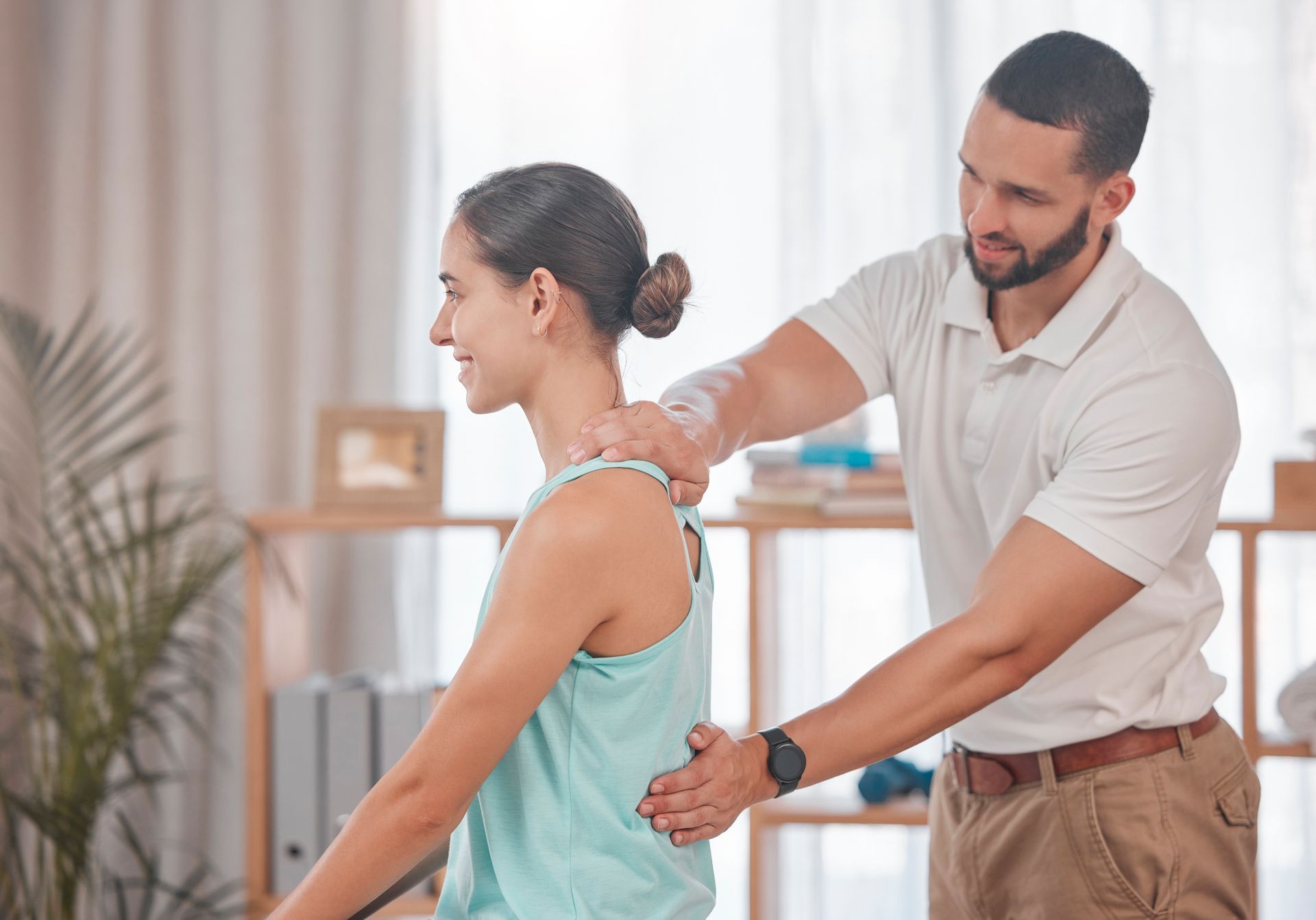 A man is helping a woman stretch her back in a living room.