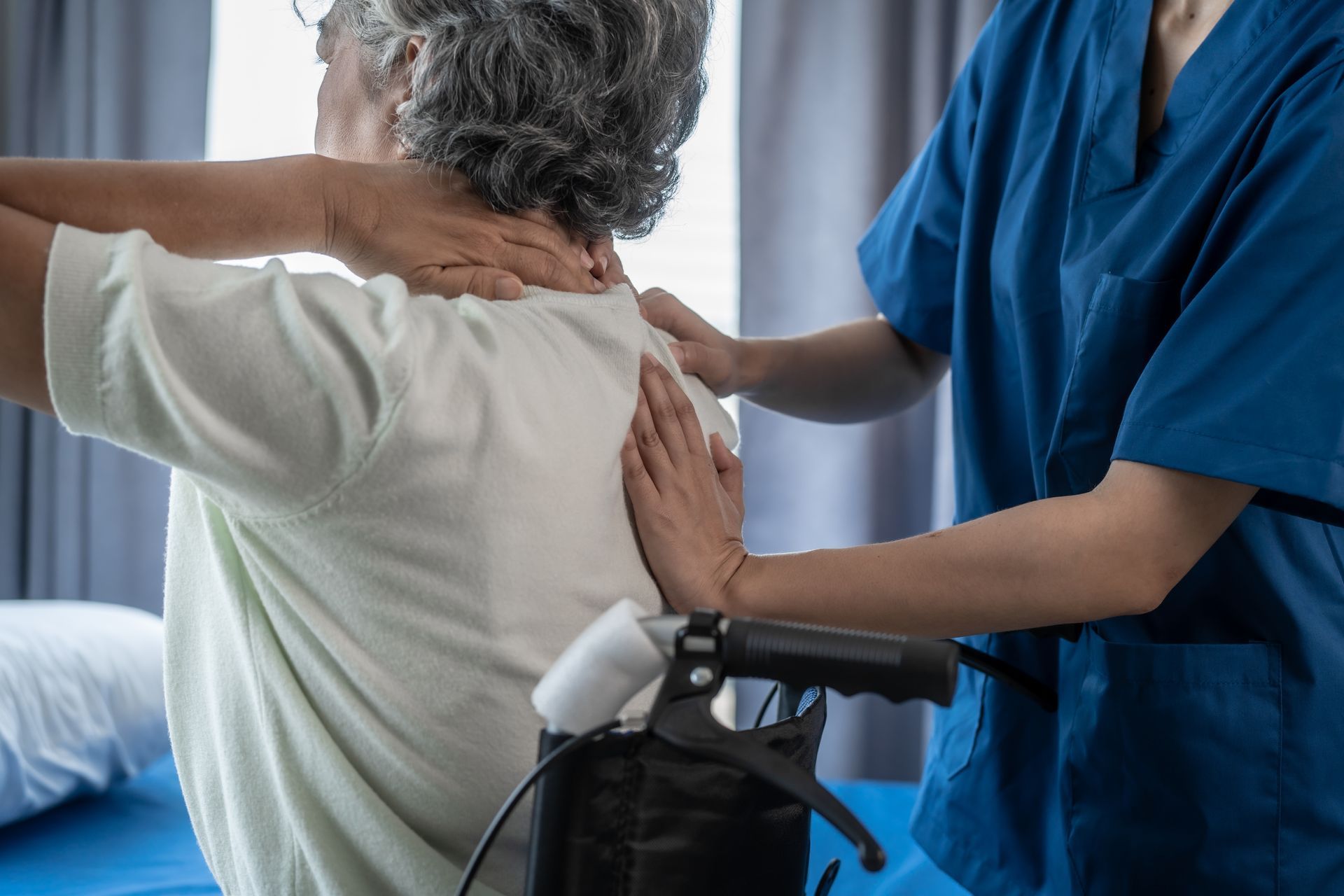 An elderly woman in a wheelchair is getting a massage from a nurse.