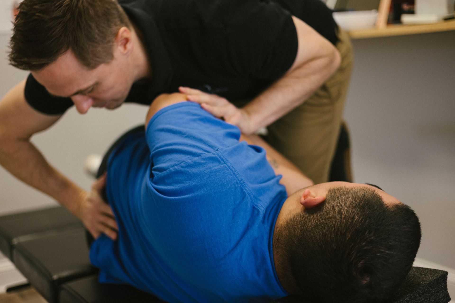 A man is laying on a table getting a massage from a doctor.