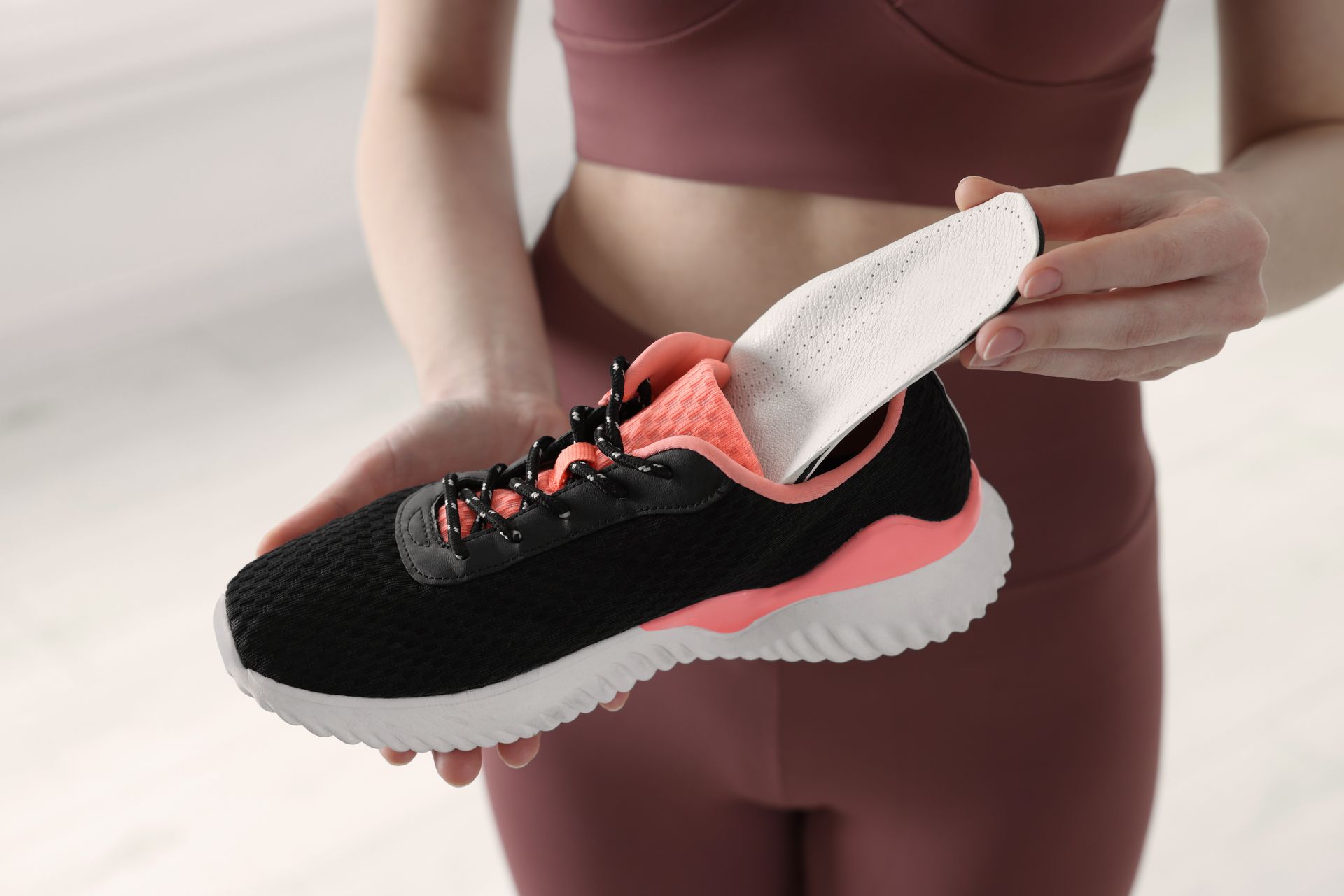 A woman is holding a pair of shoes in her hands.