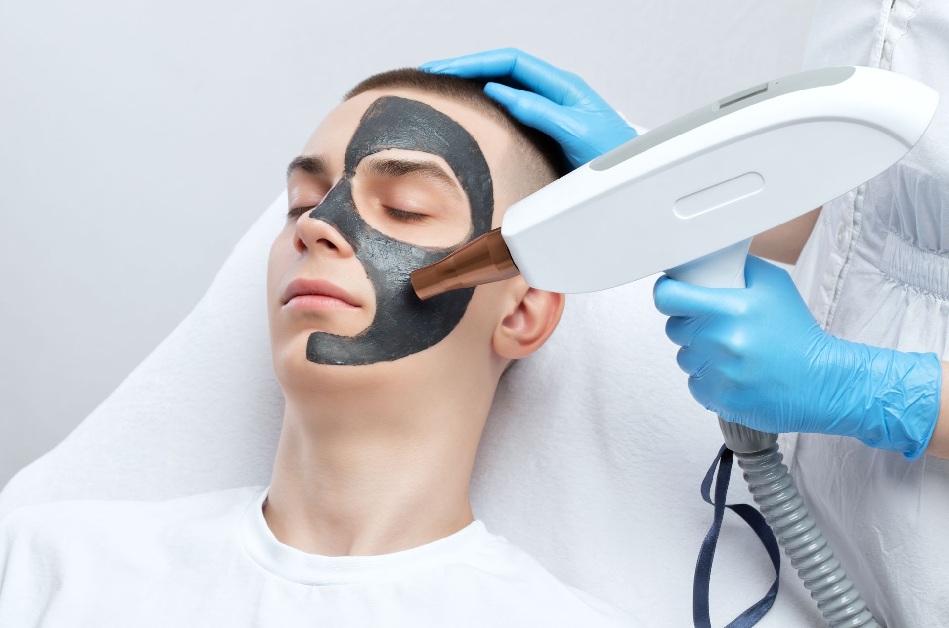 A man is getting a black mask on his face.
