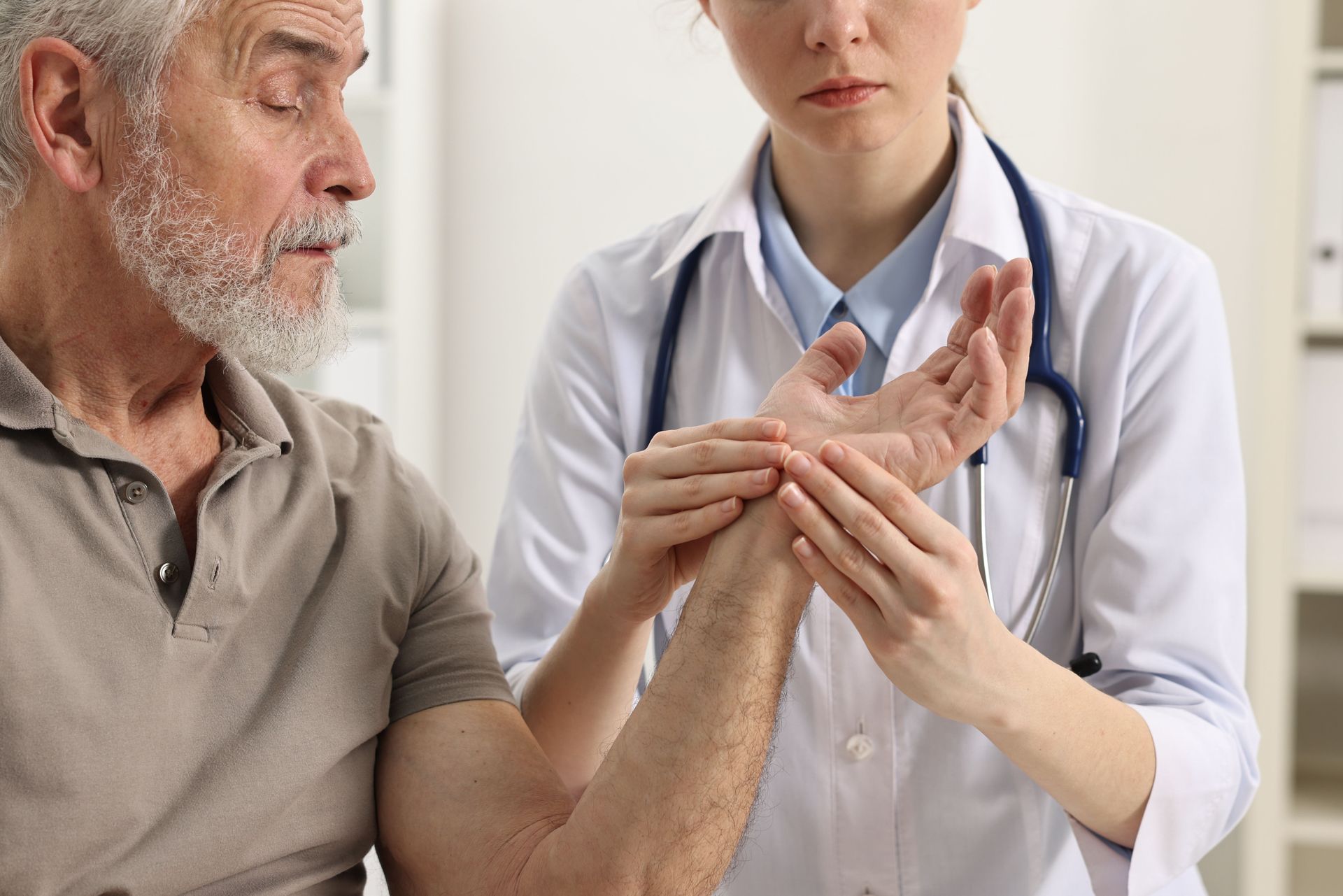 A doctor is examining an older man 's wrist.